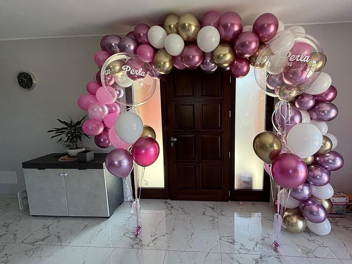 Arco organico di palloncini rosa, bianchi e oro intorno a una porta